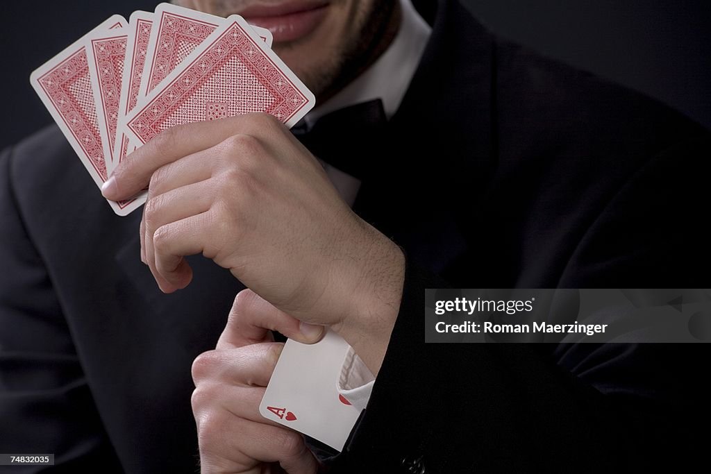 Man holding playing cards, ace in sleeve