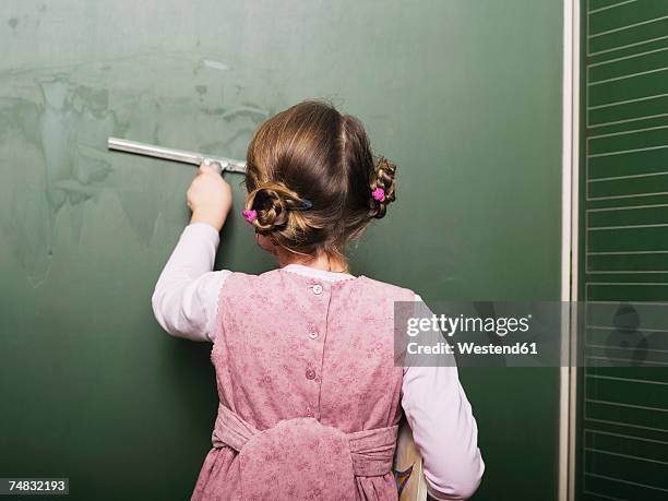 girl (5-6) wiping blackboard, rear view - chalkboard eraser stock pictures, royalty-free photos & images