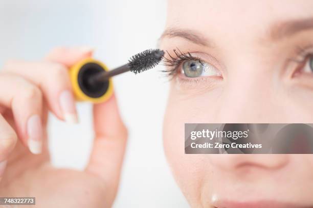 young woman applying mascara to eyelashes, close-up - applying mascara stock pictures, royalty-free photos & images