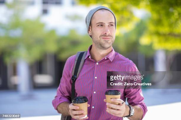 young man outdoors, holding two takeaway coffee cups - 2 cup of coffee stock pictures, royalty-free photos & images