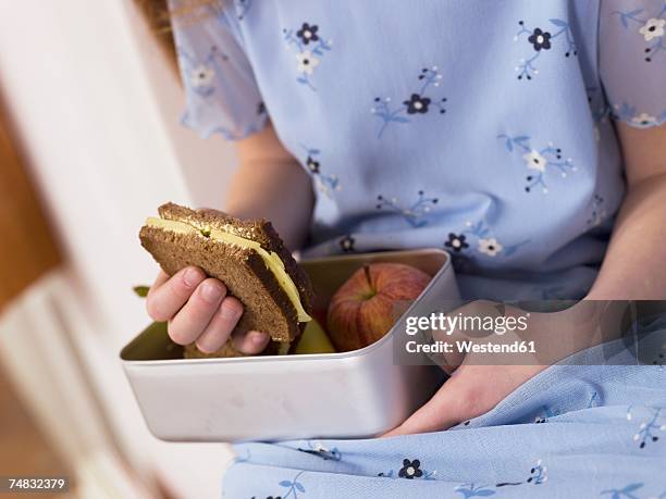 girl (4-7) sitting and holding lunch box, mid section, close-up - jause stock-fotos und bilder