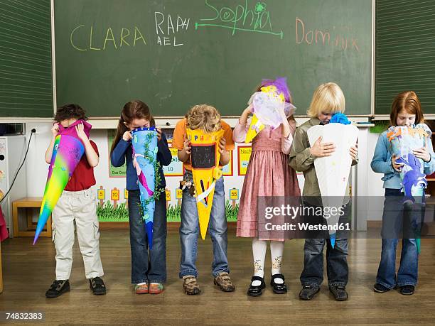 children (4-7) standing in front of blackboard looking in to school cones - first day of school stock-fotos und bilder