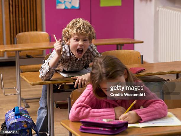 boy (4-7) shouting behind girl in class room - volume 2 ストックフォトと画像