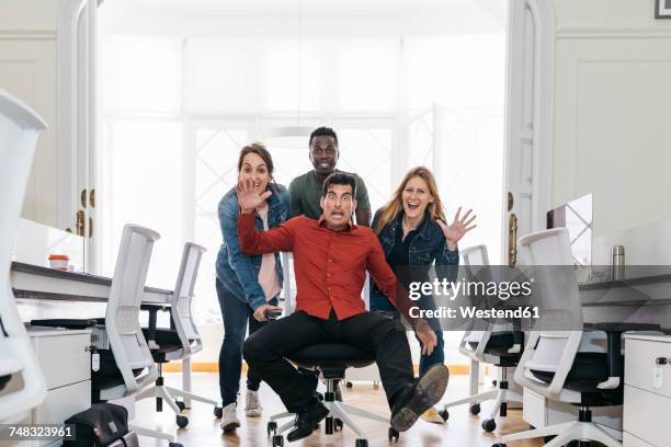 employees pushing their boss on a swivel chair through the office - winners press stock pictures, royalty-free photos & images