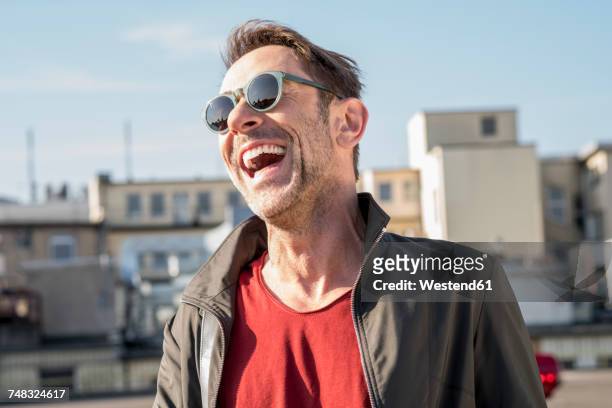 portrait of laughing mature man with stubble wearing sunglasses - männer über 40 stock-fotos und bilder
