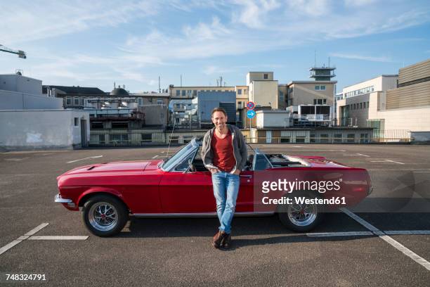 portrait of smiling mature man leaning against his parked sports car - leaning stock pictures, royalty-free photos & images