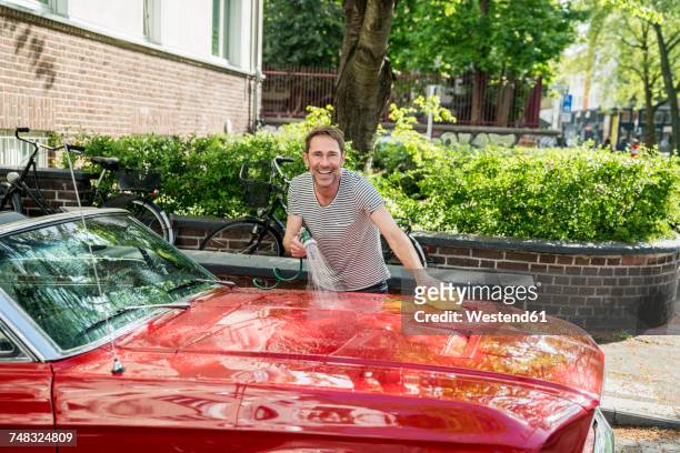 smiling mature man washing his sports car - shiny red stock pictures, royalty-free photos & images