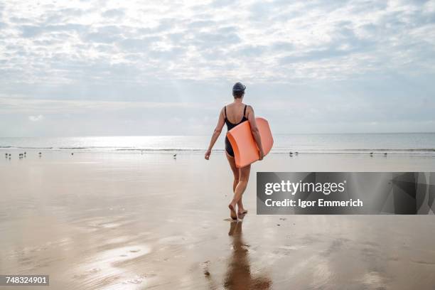 woman carrying surfboard on beach, folkestone, uk - フォークストーン ストックフォトと画像