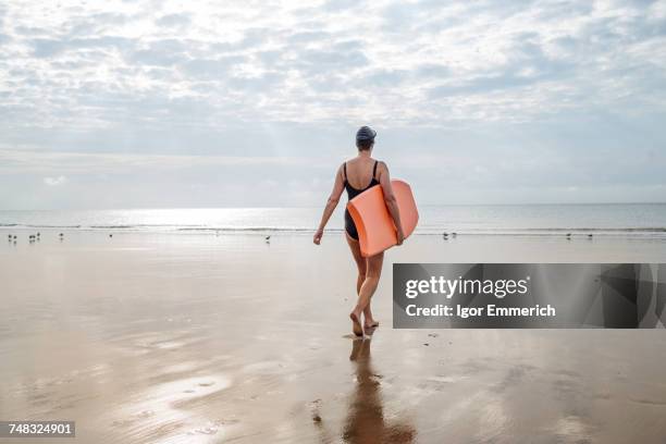 woman carrying surfboard on beach, folkestone, uk - folkestone stock pictures, royalty-free photos & images