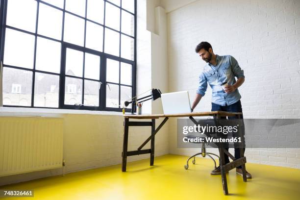 young man with coffee to go in his loft - one man only stock pictures, royalty-free photos & images