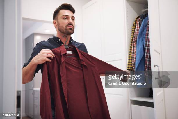 man choosing shirt from closet - choosing stock pictures, royalty-free photos & images