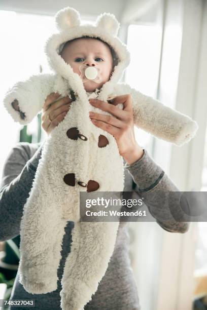 mother holding up baby in a polar bear costume - funny polar bear stock pictures, royalty-free photos & images