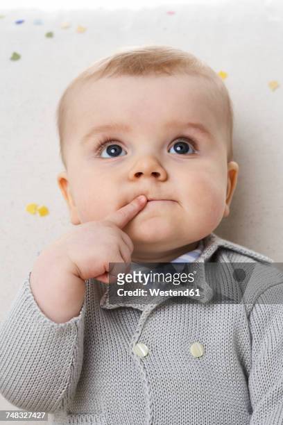 portrait of pensive baby boy with finger on his mouth - be silent stock-fotos und bilder