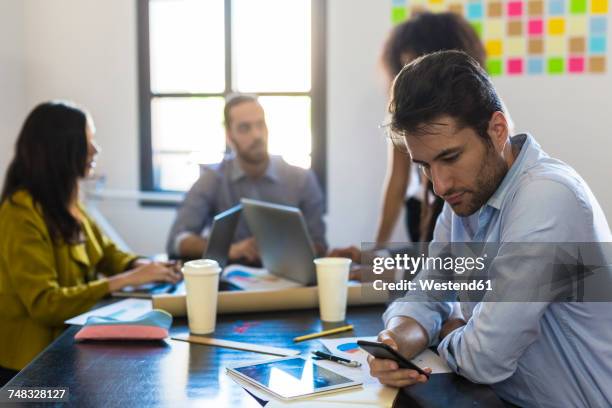 businessman checking cell phone during a meeting in office - omlaag kijken stockfoto's en -beelden