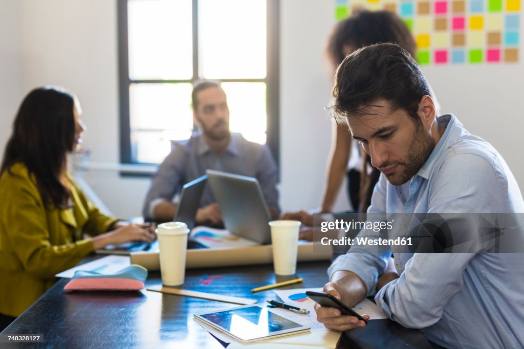 Businessman checking cell phone during a meeting in office