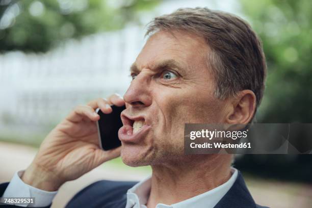 portrait of angry mature businessman outdoors on the phone - anger stock pictures, royalty-free photos & images