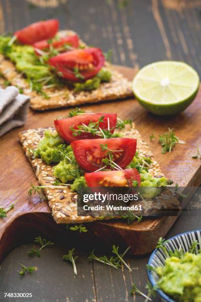 crispbread with seeds, avocado cream, tomato slices and cress - knäckebrot stock-fotos und bilder
