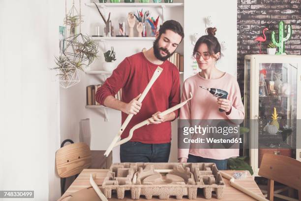 young couple assembling flat-pack stool at home - montar fotografías e imágenes de stock