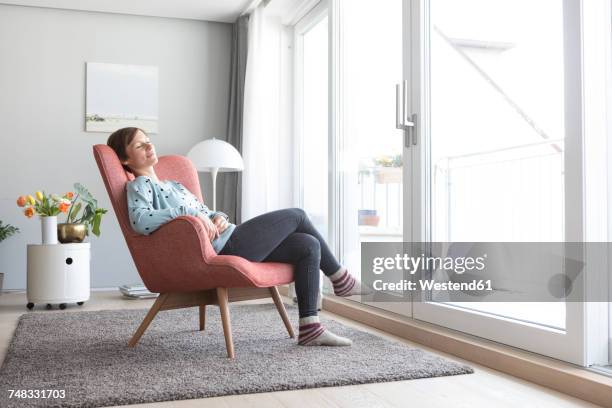 woman relaxing on armchair at home - armchair stock pictures, royalty-free photos & images