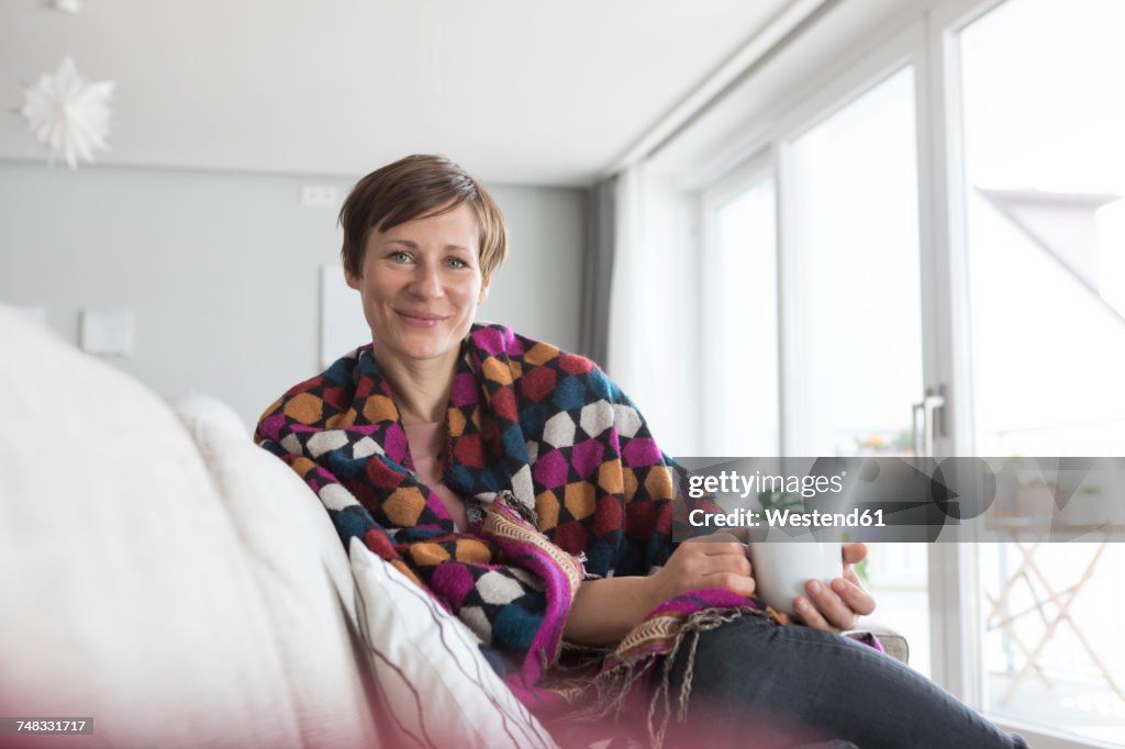 Portrait of smiling woman relaxing with cup of coffee on the couch
