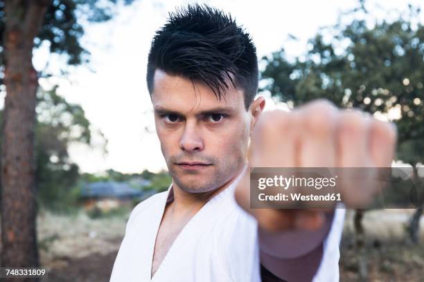 challenging man showing his fist doing a martial arts pose - strictness stock pictures, royalty-free photos & images