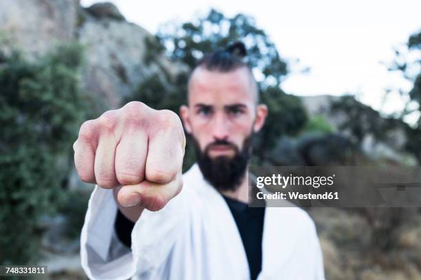 challenging man showing his fist doing a martial arts pose - strictness stock pictures, royalty-free photos & images