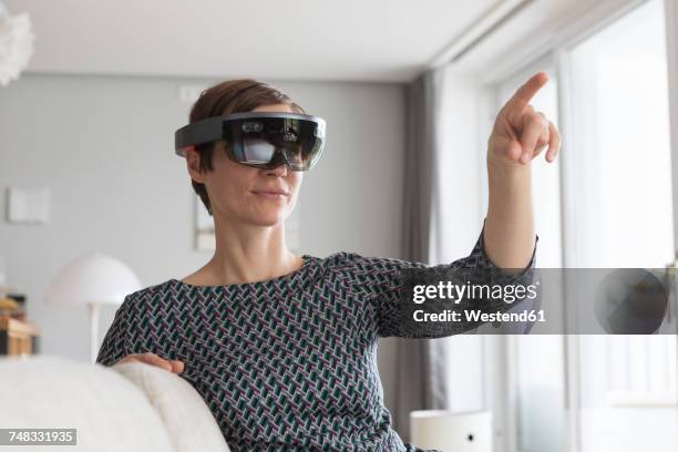 woman at home using augmented reality glasses at home - sensory perception stock photos et images de collection