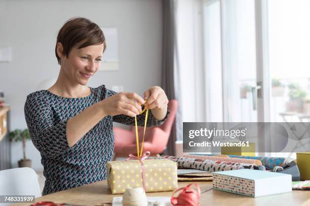 woman wrapping gifts - smiling tie stock-fotos und bilder