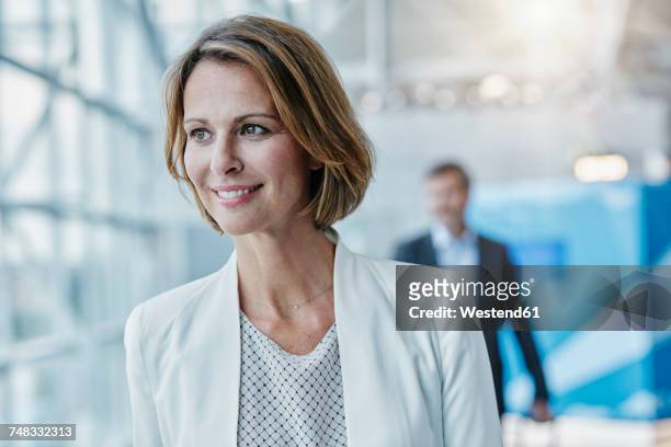 smiling businesswoman at the airport looking sideways - businesswoman airport stock pictures, royalty-free photos & images