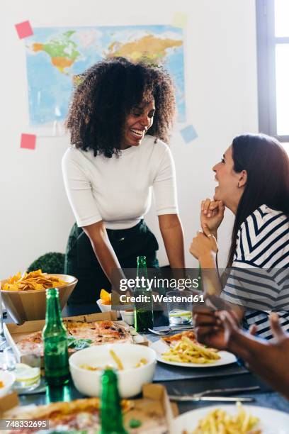 two happy young women at dining table - world pizza day stock pictures, royalty-free photos & images