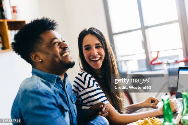 happy couple with laptop at dining table - young couple dining stock pictures, royalty-free photos & images