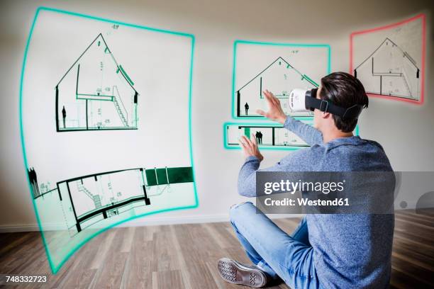 man in apartment wearing vr glasses exploring house - erweiterte realität stock-fotos und bilder