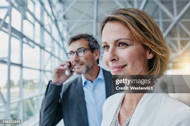 smiling businesswoman and businessman on cell phone at the airport - businesswoman talking smartphone stock-fotos und bilder