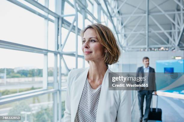confident businesswoman at the airport looking out of window - airport frankfurt stock pictures, royalty-free photos & images