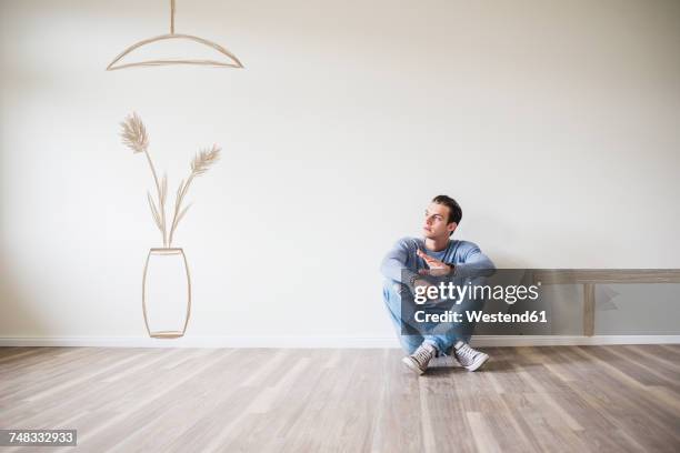 young man in new home sitting on floor thinking about interior decoration - looking around stock pictures, royalty-free photos & images