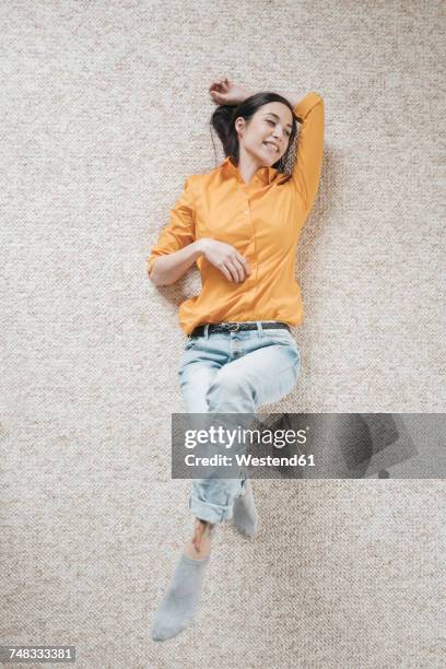 young woman relaxing on carpet - liegen stock-fotos und bilder