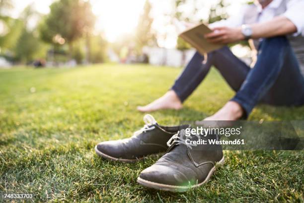 unrecognizable businessman in the city park sitting on grass reading book - barefoot men 個照片及圖片檔