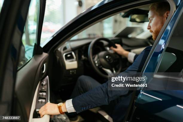 businessman testing car in car dealership - car dealership imagens e fotografias de stock