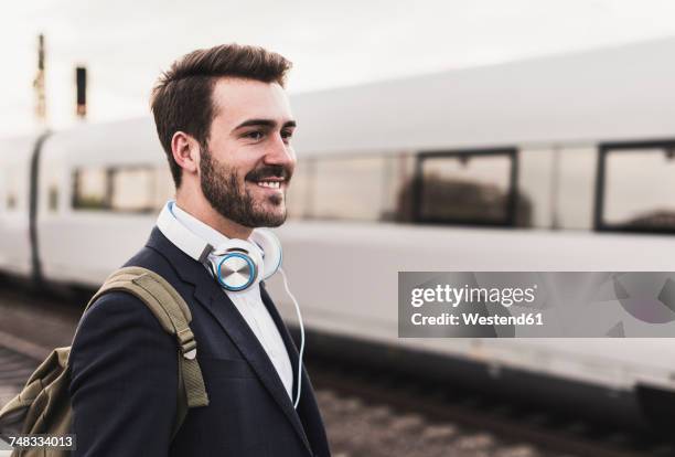 smiling young man on platform as train coming in - bart zug stock-fotos und bilder