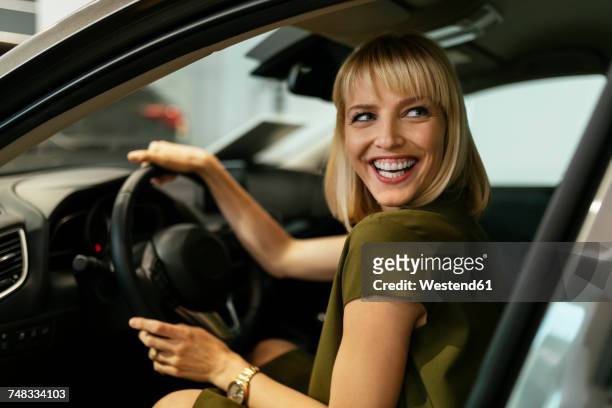 blond woman choosing new car in car dealership - kaufen stock-fotos und bilder