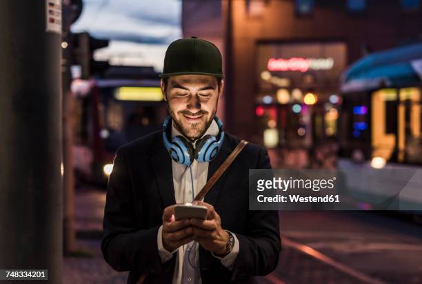 young man in the city checking cell phone in the evening - people on buses stockfoto's en -beelden