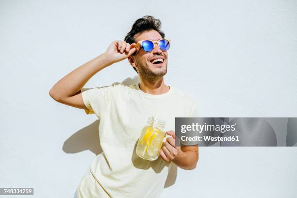 young an with sunglasses and lemonade in front white wall - gafas de sol fotografías e imágenes de stock