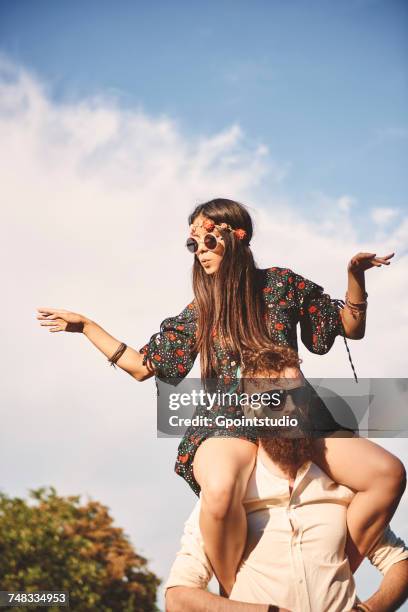 young boho woman dancing on boyfriends shoulders at festival - hippie photos et images de collection
