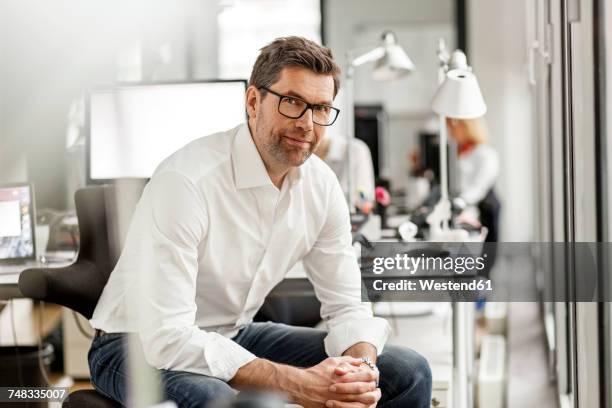 portrait of businessman at desk in office - business man desk stock-fotos und bilder