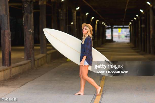 young female surfer carrying surfboard in underpass, santa monica, california, usa - surfing santa stock pictures, royalty-free photos & images