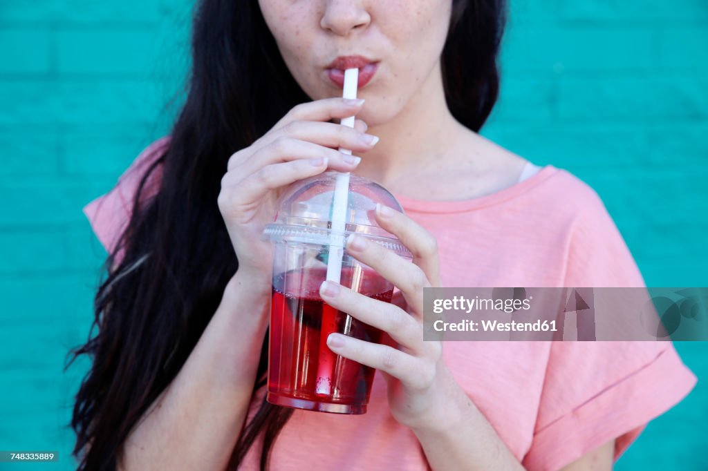 Young woman drinking soft drink, partial view