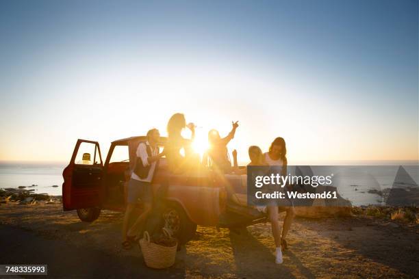 happy young people outside pick up truck at the coast at sunset - strand party stockfoto's en -beelden