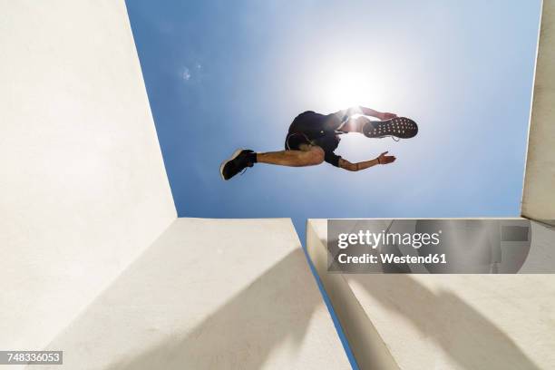 man jumping in the city during a parkour session - licht von unten stock-fotos und bilder