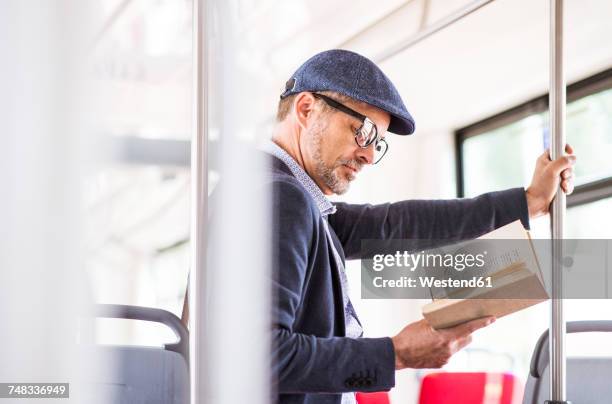 man in bus reading book - man riding bus stock pictures, royalty-free photos & images