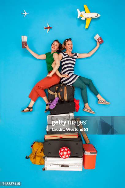 friends sitting on pile of luggage waiting for departure, holding passports and tickets - offbeat documentation foto e immagini stock